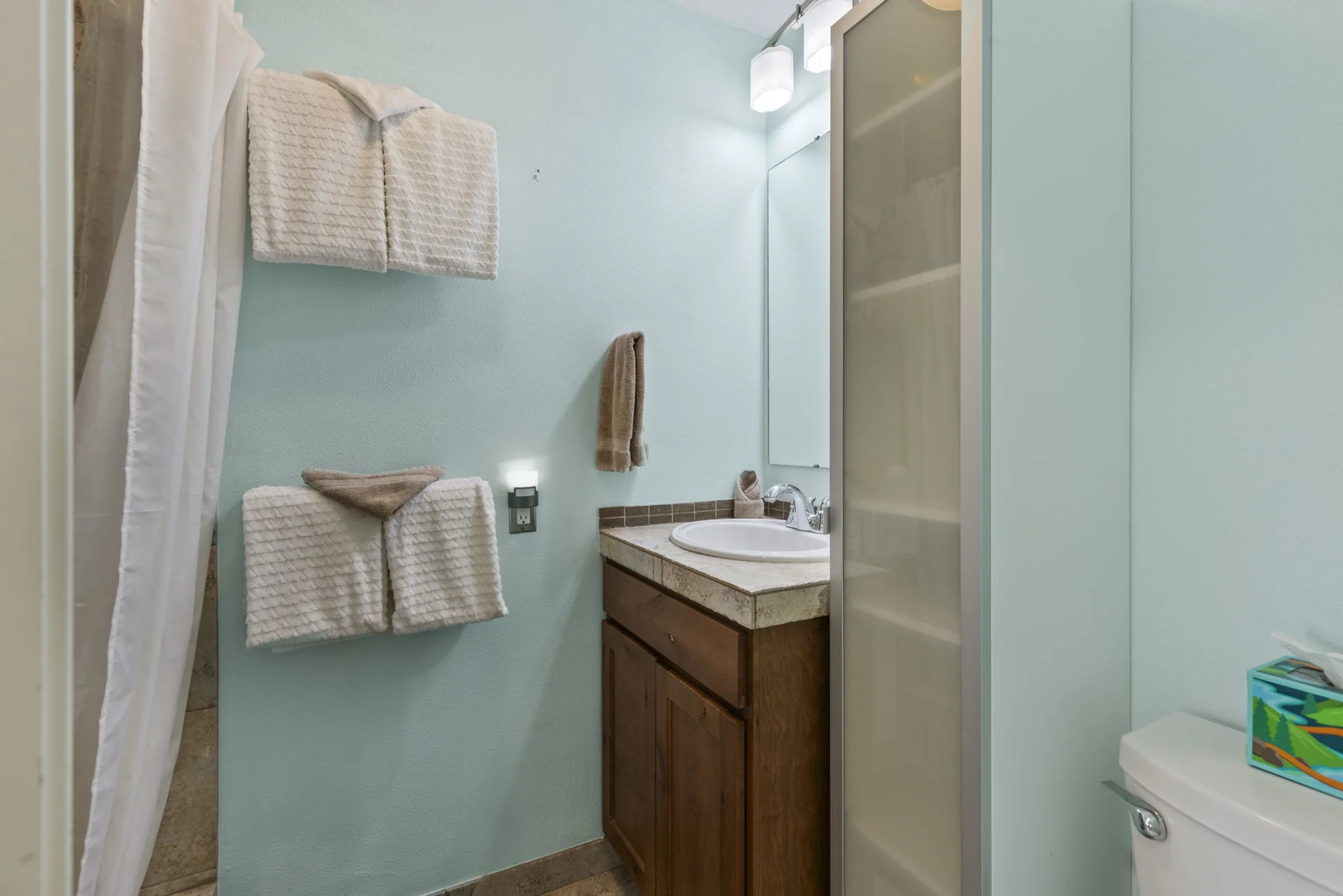 Trailside Retreat, Blue-walled bathroom with folded towels, vanity, and toilet, luxury vacation rental in Silverthorne, Colorado