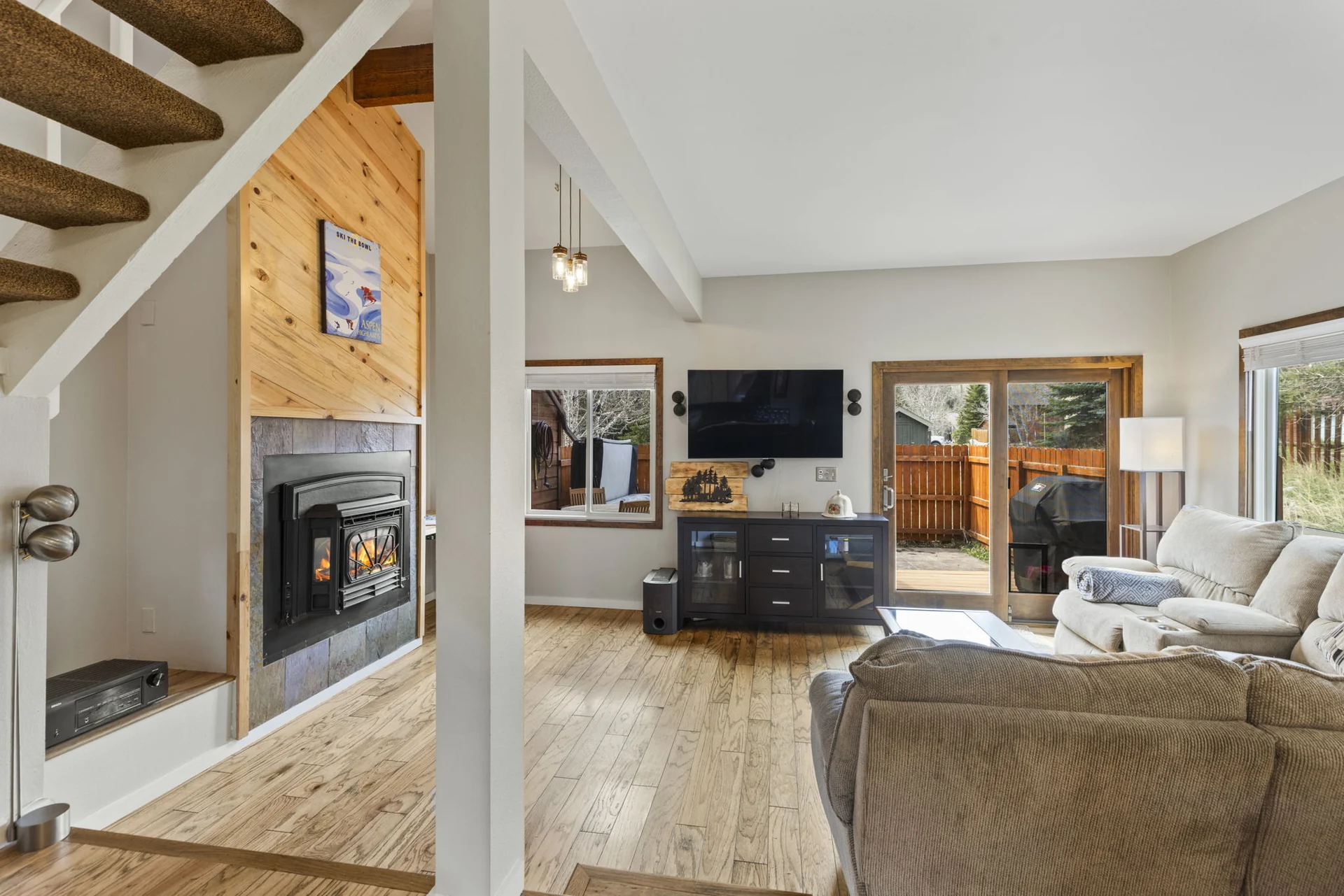 Trailside Retreat, Living room with fireplace, television, stairs, and patio door, luxury vacation rental in Silverthorne, Colorado