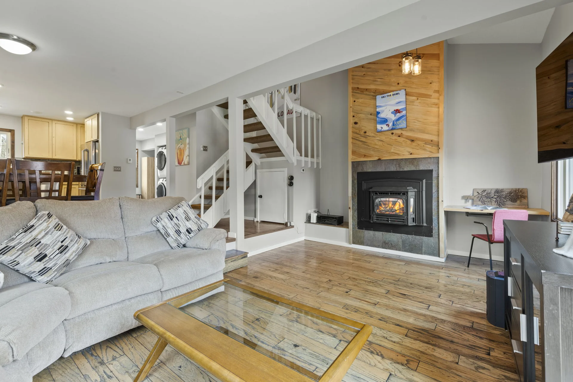 Trailside Retreat, Living room seating with a fireplace, staircase, and kitchen beyond, luxury vacation rental in Silverthorne, Colorado